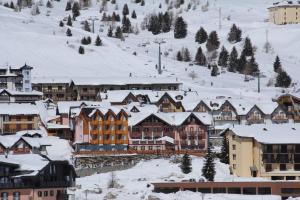 een stad bedekt met sneeuw met gebouwen bij Hotel Residence Dahu in Passo del Tonale