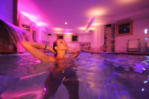 a woman is laying in a swimming pool at Hotel Residence Dahu in Passo del Tonale