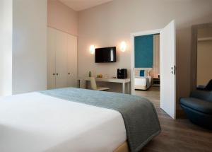 a bedroom with a white bed and a blue chair at Occidental Faro in Faro