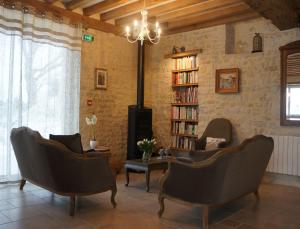 een woonkamer met 2 stoelen en een boekenplank bij B&B Les Oiseaux de Passage in Isigny-sur-Mer