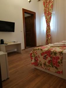 a bedroom with a bed and a table and a television at Pensiunea Geostar 2 in Curtea de Argeş