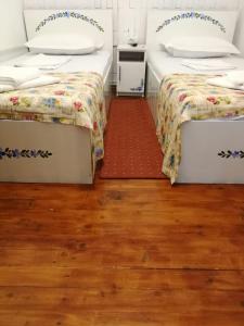 two beds in a room with wooden floors at Pensiunea Geostar 2 in Curtea de Argeş