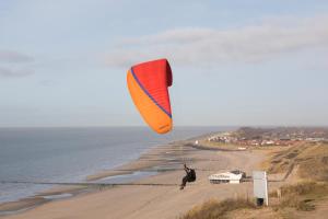 a person is flying a kite on the beach at Duinhotel Tien Torens in Zoutelande