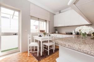 a white kitchen with a table and chairs in it at Barbara's House - Minho's Guest in Braga