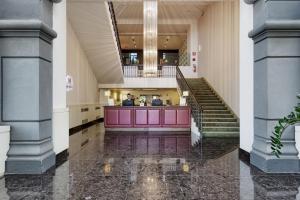 a lobby of a building with stairs and a pink counter at Italiana Hotels Milan Rho Fair in Rho