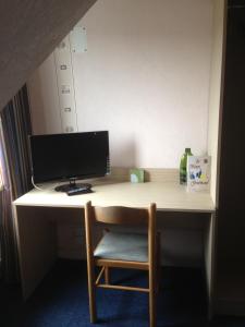 a desk with a computer on top of it at Hôtel La Tour D'Auvergne in Pont-lʼAbbé +5 photos