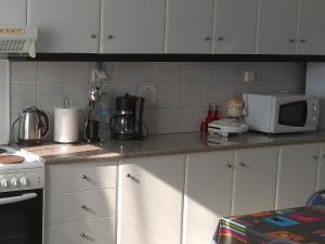 a kitchen with white cabinets and a white microwave at Zante Green View in Ambelókipoi