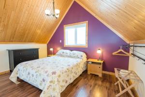 ein Schlafzimmer mit einem Bett und einer lila Wand in der Unterkunft Chalets Valmont in Cap-Chat