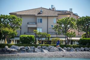 a man standing on the rocks in front of a building at Hotel Du Lac et Bellevue in Bardolino