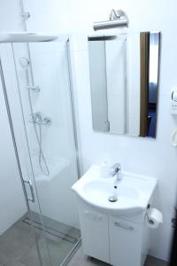 a white bathroom with a shower and a sink at Hotel Colnus in Kolno