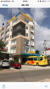 un autobús amarillo estacionado frente a un edificio en Ngọc Nam Hotel, en La Gi