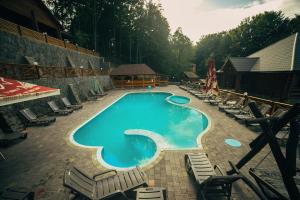 a large swimming pool with lounge chairs and chairs around it at Sadyba Sribne Dzherelo in Ilʼnytsya