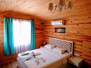 1 dormitorio con 1 cama en una habitación de madera en Simge Pension, en Cıralı