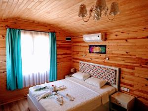 a bedroom with a bed in a wooden room at Simge Pension in Cıralı