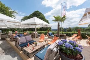 a patio with chairs and tables and umbrellas at Mercure Hotel Bielefeld Johannisberg in Bielefeld