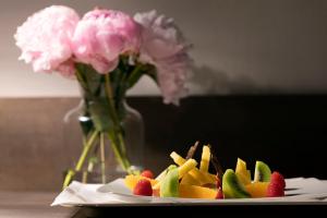 un plato de fruta en una mesa con un jarrón con flores en Albavilla Hotel & Co, en Albavilla
