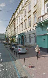 リヴィウにあるOnLviv Apartments Teatralna 23の建物のある街路を歩く男