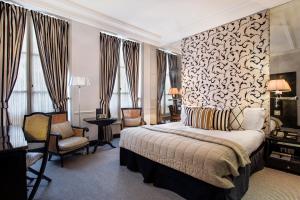 a hotel room with a bed and a chair at Castille Paris – Starhotels Collezione in Paris