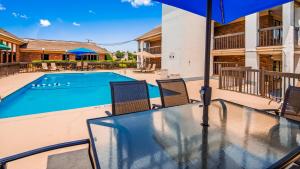 einen Tisch mit Stühlen und einen Sonnenschirm neben einem Pool in der Unterkunft Quality Inn & Suites Fayetteville I-95 in Fayetteville