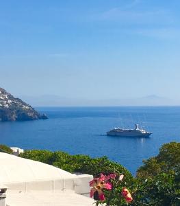 a large boat in the water with a ship at Hotel Villa Delle Palme in Positano in Positano