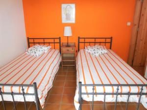 2 camas en una habitación con paredes de color naranja en Casas de Lava en Ribeirinha
