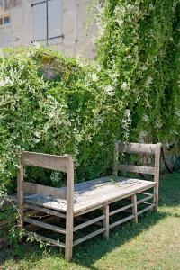 a wooden bench sitting in the grass next to a bush at Domaine de L'Isle Basse in Fontanes