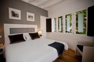 a bedroom with a white bed and two windows at Hotel Sitges in Sitges