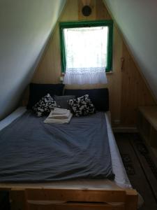 Bett in einem kleinen Zimmer mit Fenster in der Unterkunft Domek nad jeziorem in Wielki Głęboczek