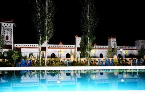 a large building with a swimming pool at night at Riad Mimouna De Timnay in Aguelmous