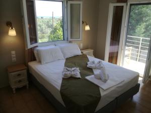 a bed with white bows on it with a window at Rastoni Guest House Skopelos in Skopelos Town