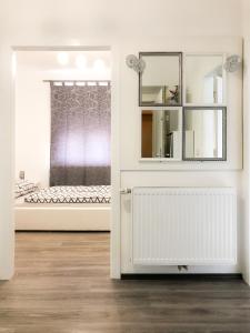 Cette chambre blanche comprend un lit et un miroir. dans l'établissement Apartment Lara, à Vienne