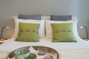 Una cama con almohadas verdes y una bandeja de comida. en Oki Doki Studios en Milán