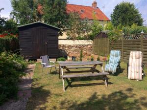 een picknicktafel en stoelen in een tuin met een schuur bij Kilreany in Sidmouth