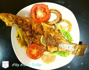 une assiette blanche de nourriture avec du poisson et des légumes dans l'établissement City Centre Lodge, à Anurâdhapura