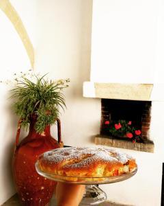 a pizza on a plate next to a vase at Masseria Marico in Castellaneta