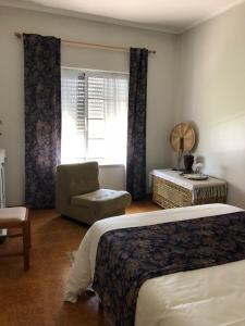 a bedroom with a bed and a chair and a window at Quinta Nova do Almeida in Alcobaça