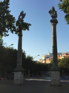 dos columnas altas en una calle con edificios en el fondo en APARTAMENTOS HÉRCULES SEVILLa, en Sevilla