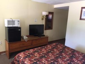 a hotel room with a bed and a television on a dresser at Elmwood Motor Lodge in Boscawen