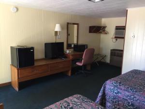 a hotel room with a desk with a television and a bed at Elmwood Motor Lodge in Boscawen +10 photos