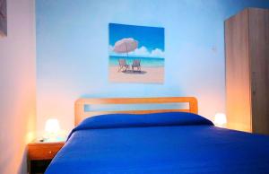 ein Schlafzimmer mit einem Bett mit blauer Tagesdecke und einem Strand in der Unterkunft Dimora Il Girasole in Torre San Giovanni Ugento