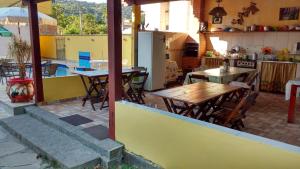 un patio con mesas y sillas y una cocina. en Recanto Sol de Verão, en Paraty