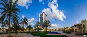 a view of a hotel with palm trees and buildings at The Baron Hotel - Karbala in Karbalāʼ