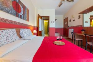 a bedroom with a bed with a red blanket and two glasses of wine at Aurora Rooms in Lecce