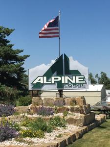 una señal de entrada a un lodge alpino con bandera en Alpine Lodge, en Red Lodge