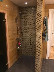 a bathroom with a shower with a tiled wall at Wonderful wooden house next to lake and Stockholm archipelago in Boo