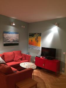 uma sala de estar com um sofá vermelho e uma televisão em Wonderful wooden house next to lake and Stockholm archipelago em Boo