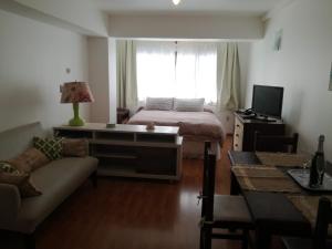 1 dormitorio con cama, sofá y ventana en vividei en San Carlos de Bariloche