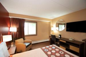a hotel room with a bed and a desk and a television at Super 8 by Wyndham Brooklyn Center/MPLS in Brooklyn Center