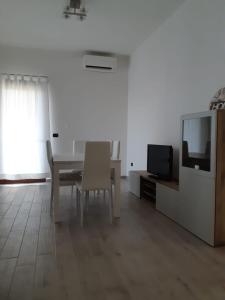 ein weißes Wohnzimmer mit einem Tisch und einem TV in der Unterkunft Sa Caladroxa in Villa San Pietro