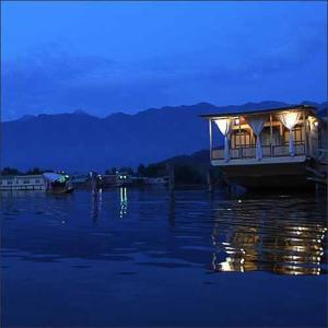 a boat with lights on the water at night at Houseboat Pride of India in Srinagar